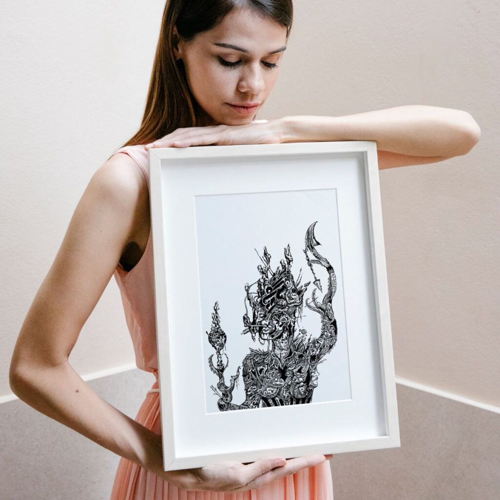 Woman holding the "goddess" poster in a white frame, displaying the poster's intricate design with a mystical, mythological figure.